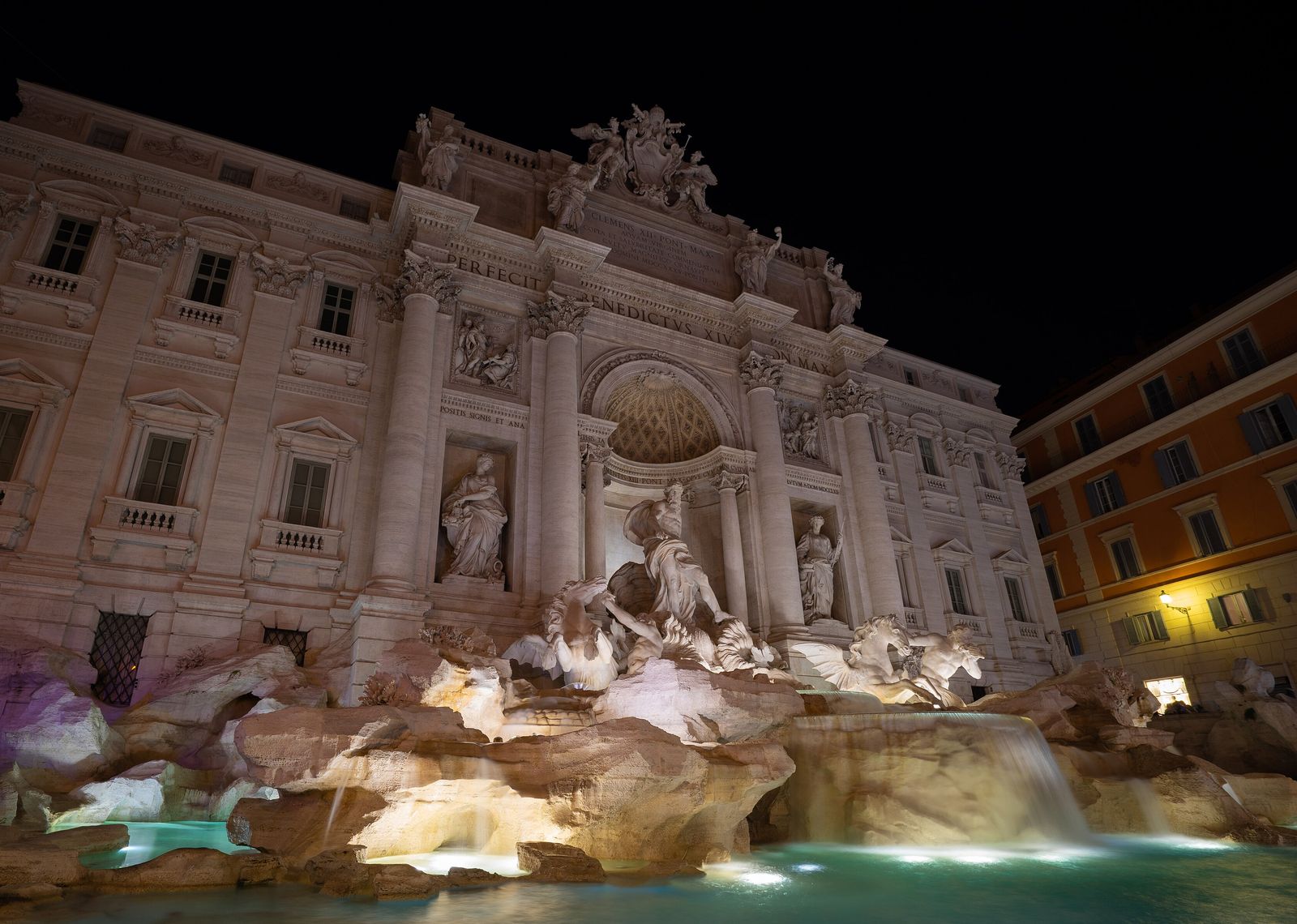 Der Trevi-Brunnen in Rom bei Nacht, angestrahlt, mit türkis beleuchtetem Wasserbecken